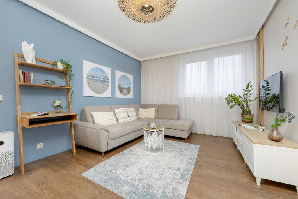 uma sala de estar com um sofá e uma mesa em Blue Apartment Słowackiego with Balcony and Parking in Gdańsk by Renters em Gdansk