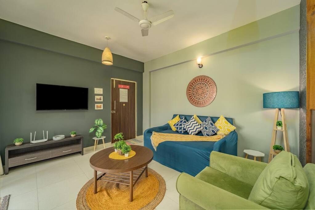 a living room with a blue couch and a tv at Earthlings : Anjuna beach- 2BHK with swimming pool in Anjuna