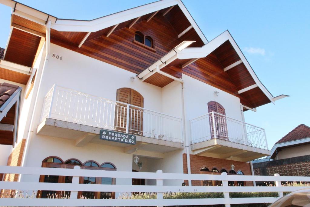 una casa con balcones de madera en un lateral en Pousada Recanto Sião, en Campos do Jordão