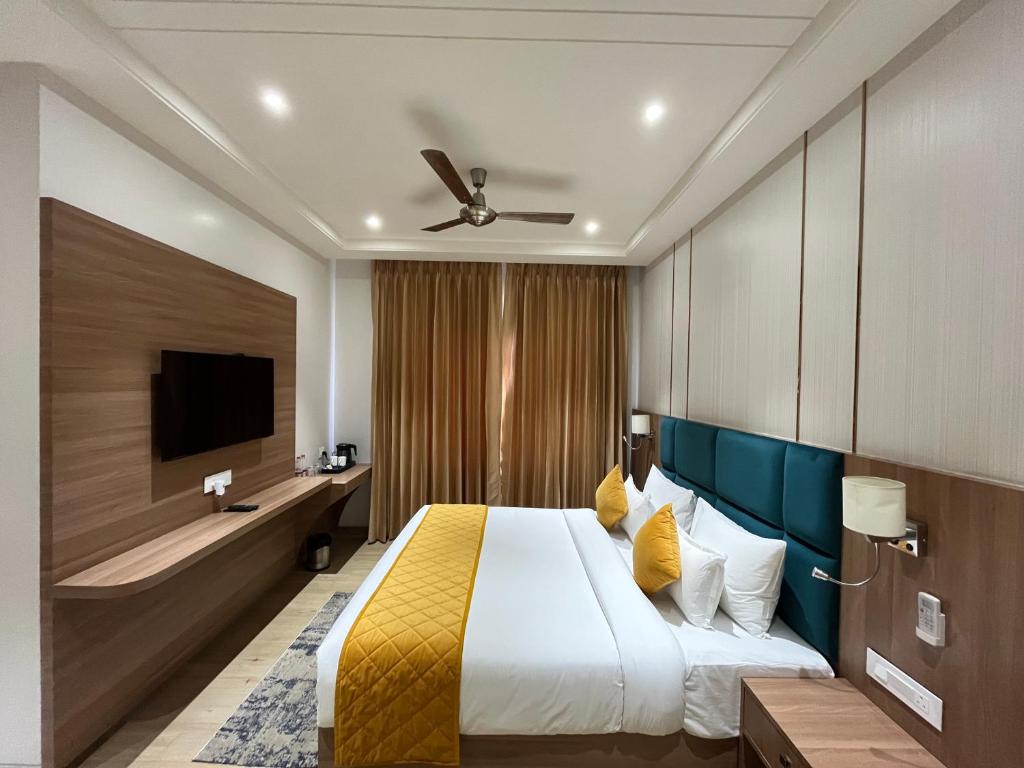 um quarto de hotel com uma cama e uma televisão de ecrã plano em Hotel Three Seasons em Vrindavan
