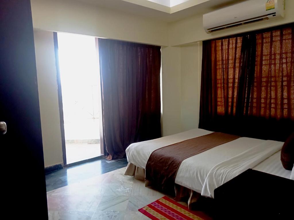 a bedroom with two beds and a window with curtains at Hotel Suite Sadaf in Kelātali
