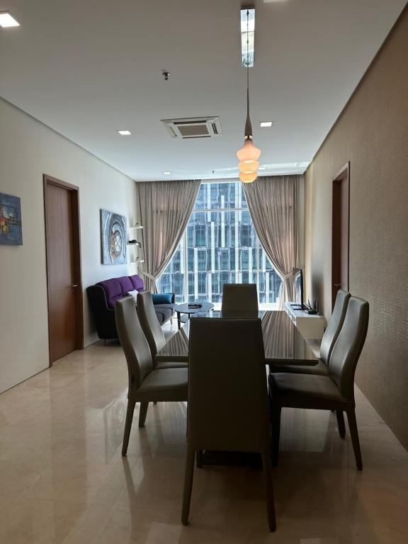 a dining room with a table and chairs and a large window at Soho Suites KLCC by Angel in Kuala Lumpur