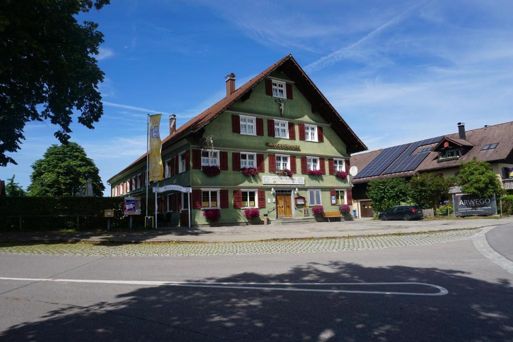 a green building with white windows on a street at Landgasthof Post in Röthenbach