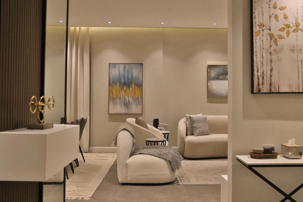 ein Wohnzimmer mit 2 Stühlen und einem Sofa in der Unterkunft شقه باثاث مودرن تقع في برج سكني فاخر in Riad