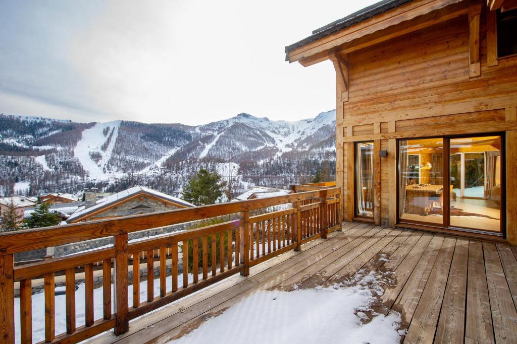 a wooden deck with a view of the mountains at Chalet Gemme - Magnifique chalet piscine sauna in Saint-Étienne-de-Tinée