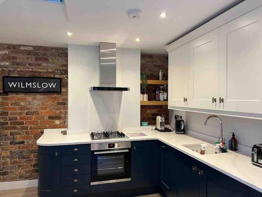 a kitchen with blue cabinets and a brick wall at Squirrels Leap - beautiful one bed apartment in Alderley Edge