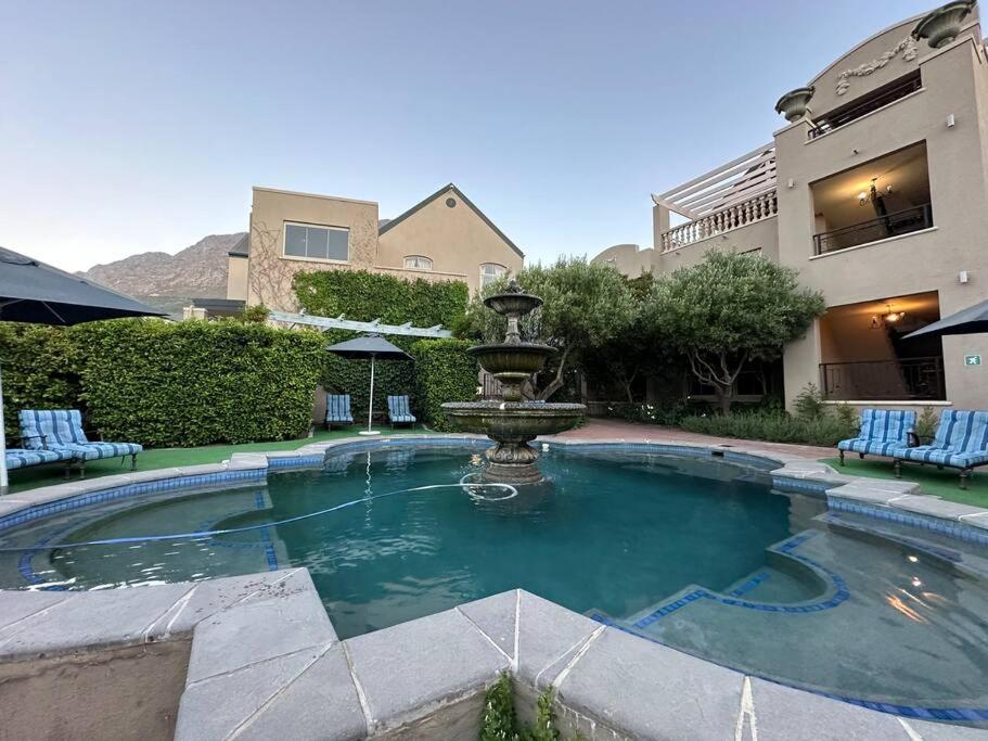 a swimming pool with a fountain in a courtyard at Mountain View 1-Bedroom Villa in Franschhoek in Franschhoek