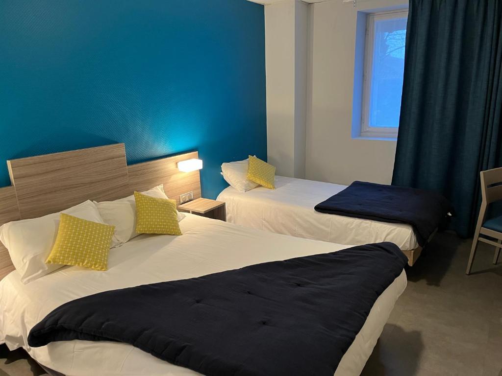 two beds in a hotel room with blue walls at Clair de Lie in Vallet