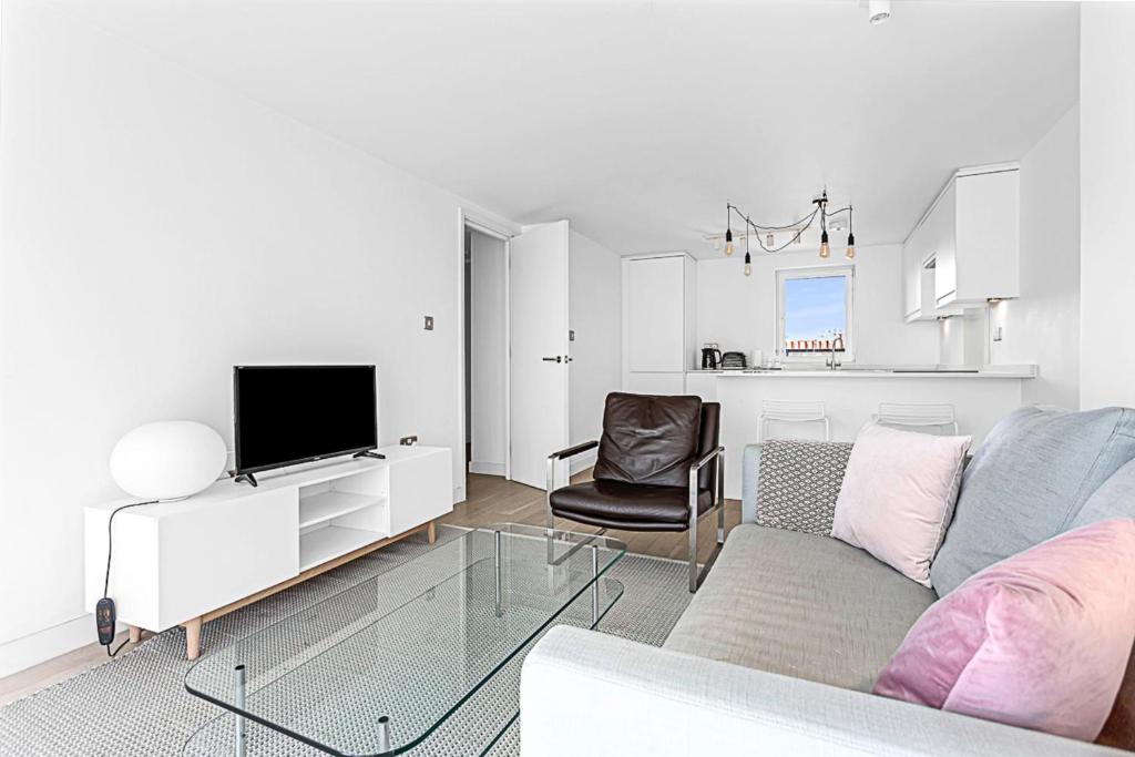 een woonkamer met een bank, een tv en een stoel bij Belgravia Apartment 29 in Londen