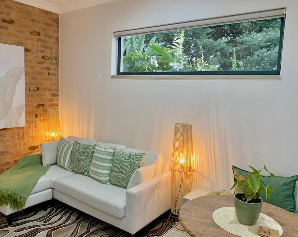 a living room with a white couch and a window at Forest Hill in Pretoria