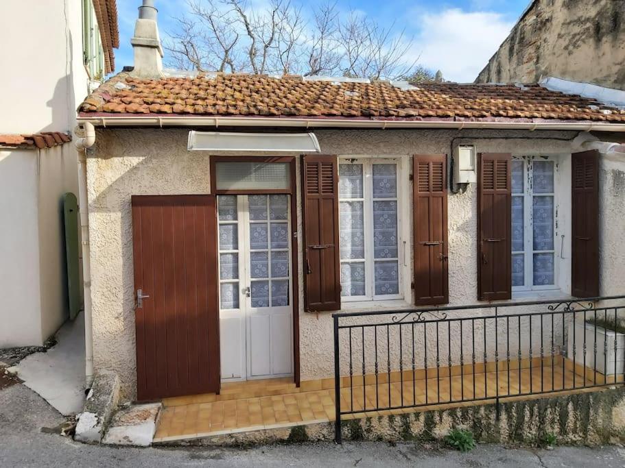 ein kleines Haus mit braunen Türen und einem Zaun in der Unterkunft Le Rove : la petite maison in Le Rove