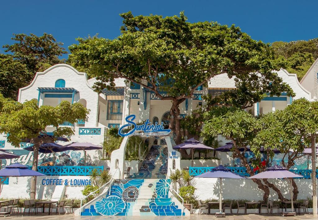 SUNTORINI BOUTIQUE HOTEL في فنغ تاو: منتجع فيه حديقة مائية فيها كراسي ومظلات زرقاء