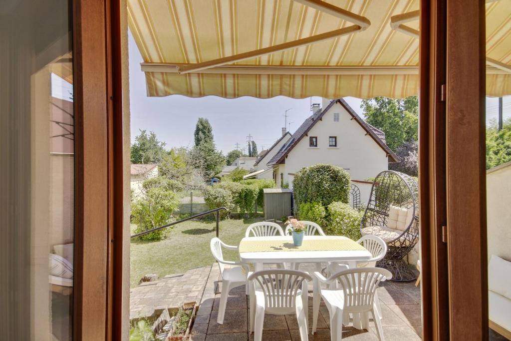 a patio with a table and chairs and a view of a house at Spacious house with garden in Neuilly-sur-Marne