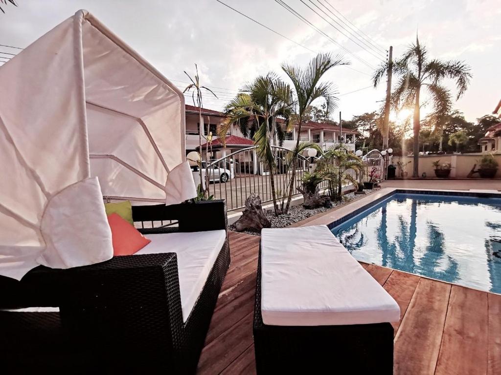 a pool with two chairs next to a swimming pool at Pool Villa 92 in Ban Nong Pru