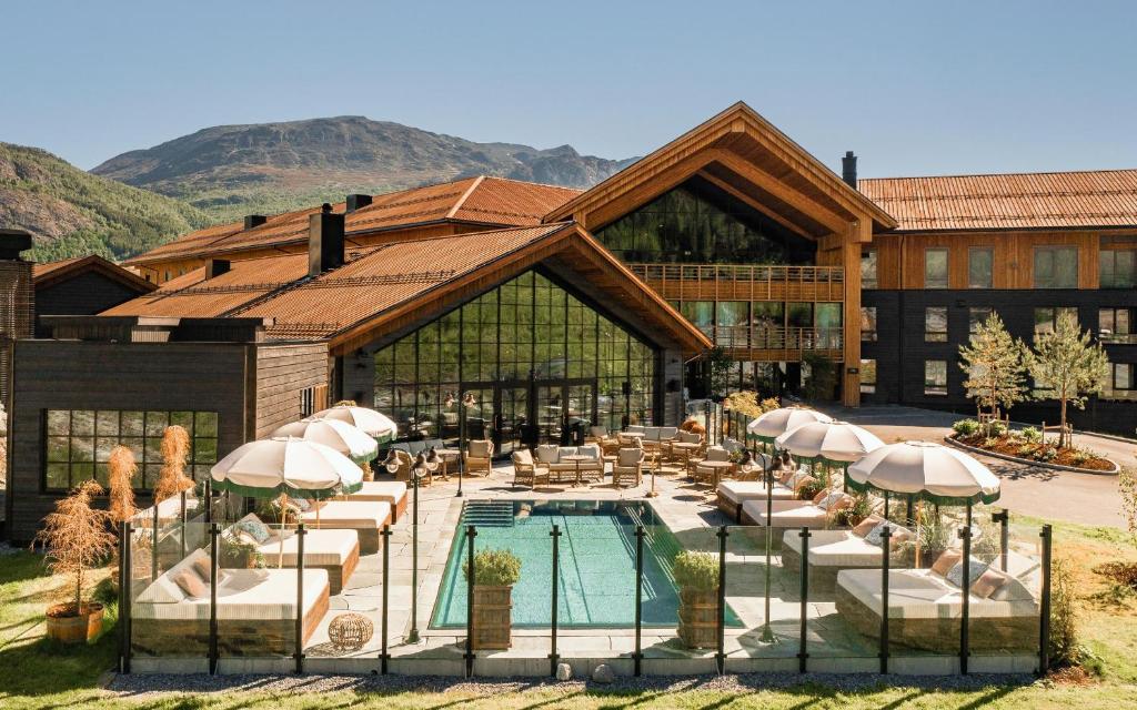 a building with a swimming pool and chairs and a building at Fýri Resort in Hemsedal