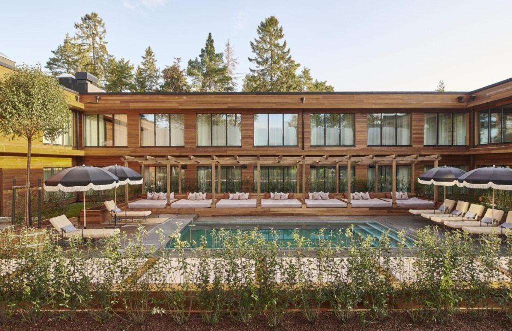 a house with a pool and chairs and umbrellas at Ellery Beach House in Lidingö