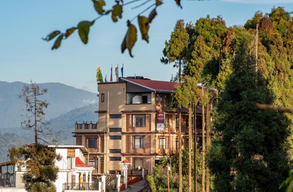 duży budynek na szczycie wzgórza z drzewami w obiekcie Summit Sherpa Mountain Hotel & Spa w mieście Kalimpong