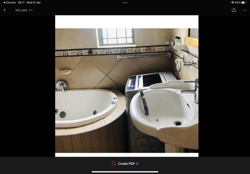 a bathroom with two sinks and a bath tub at JimmyLuh Garden Cottage in Durban