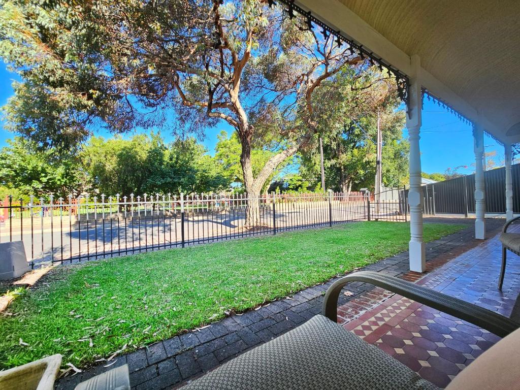 a porch with a fence and a tree and grass at Unley Retreat in Unley