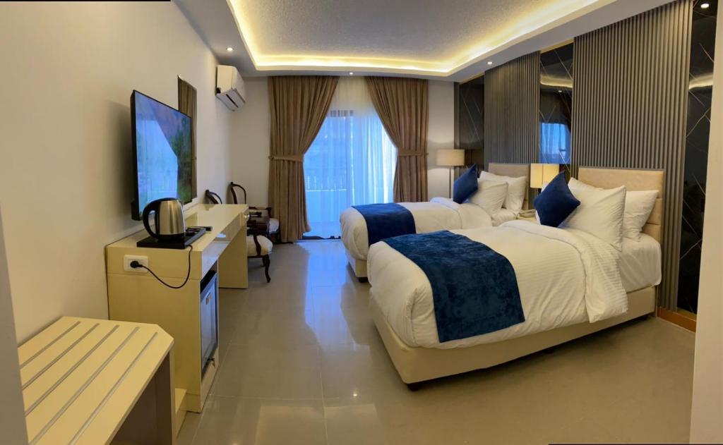 una camera d'albergo con due letti e una TV a schermo piatto di The RN Hotels a Wadi Musa