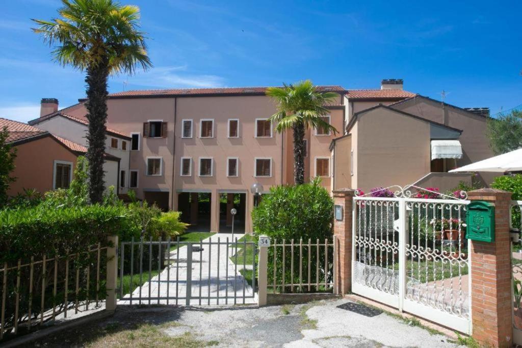 a white gate with palm trees in front of a building at N212 - Numana, quadrilocale in centro con terrazzo in Numana