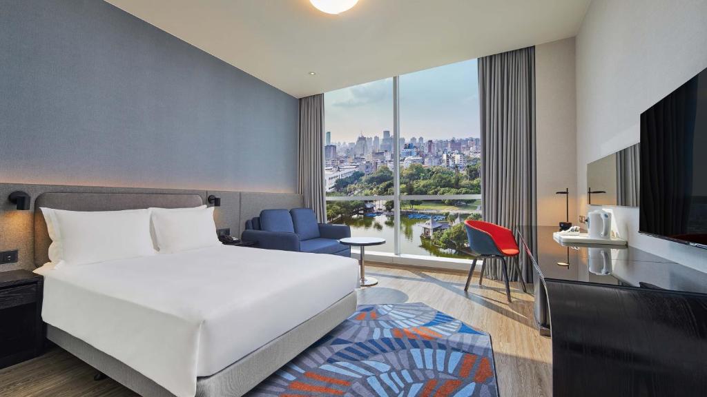 um quarto de hotel com uma cama e uma grande janela em Holiday Inn Express Taichung Park, an IHG Hotel em Taichung