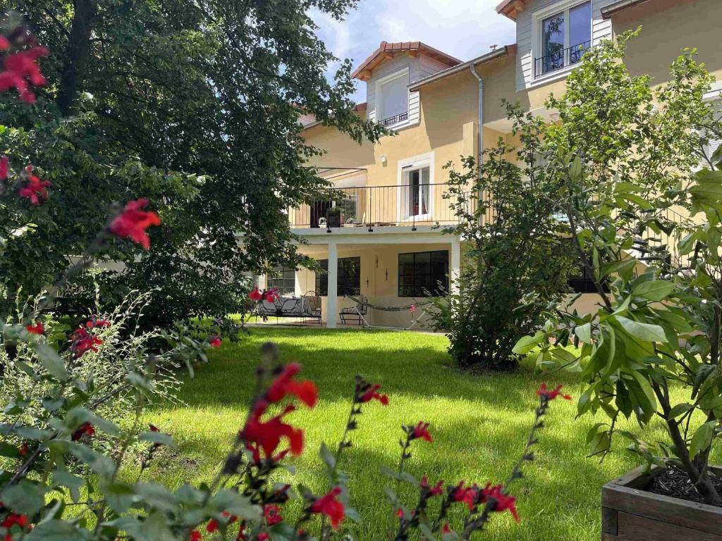 a large house with a yard with red flowers at Le Jardin du Dolaizon in Le Puy-en-Velay