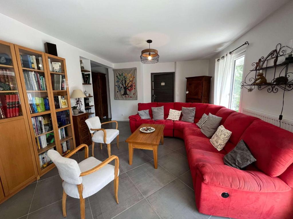 a living room with a red couch and a table at Le Jardin du Dolaizon in Le Puy-en-Velay