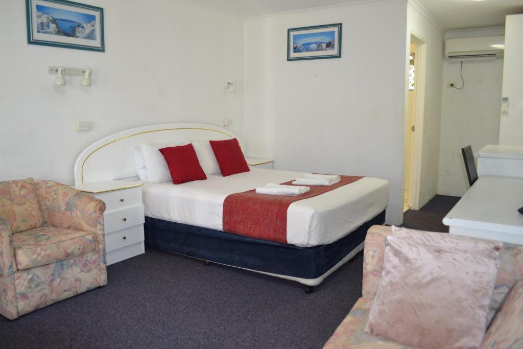 a hotel room with a bed and a chair at Calico Court Motel in Tweed Heads