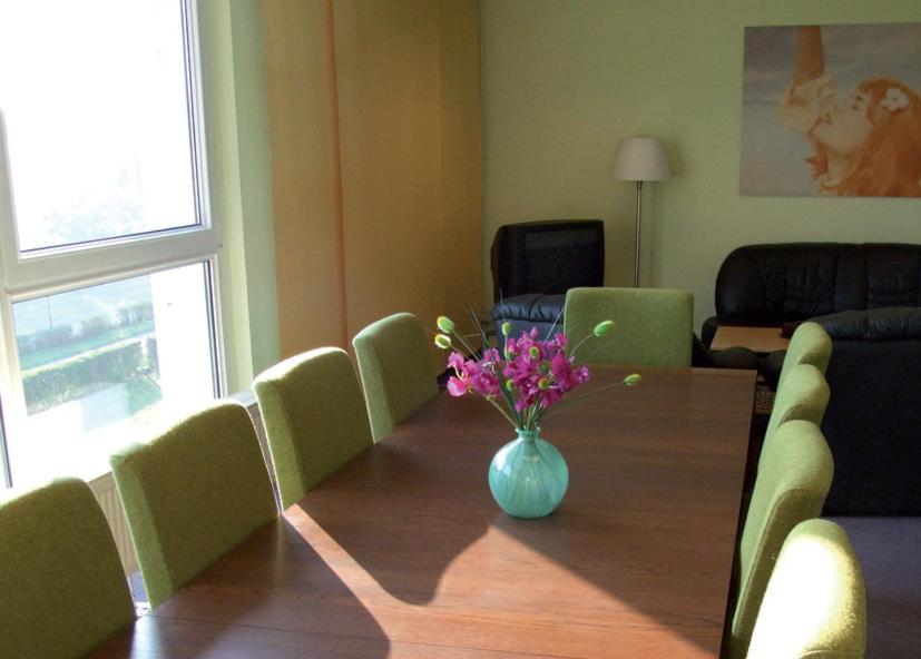 a dining room table with a vase of flowers on it at BIG Reisehotel Wolfen in Wolfen