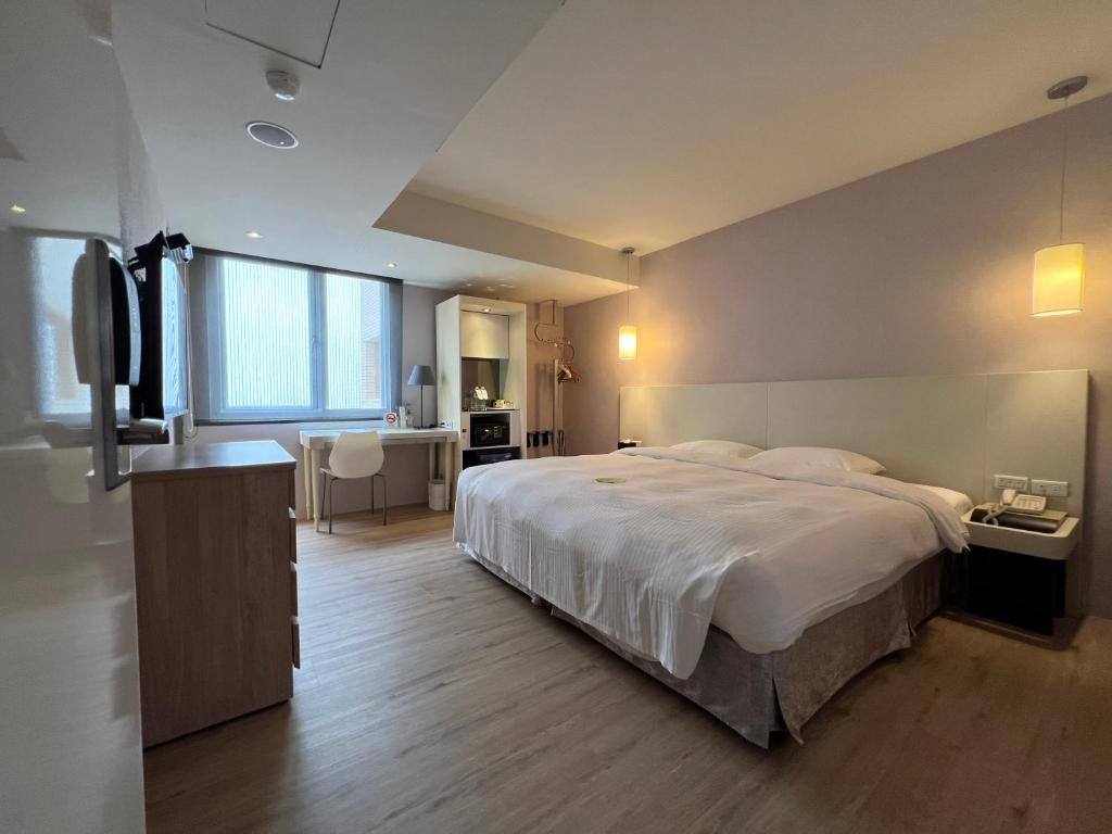 a bedroom with a large white bed and a bathroom at 台北馥華商旅 松江館 in Taipei