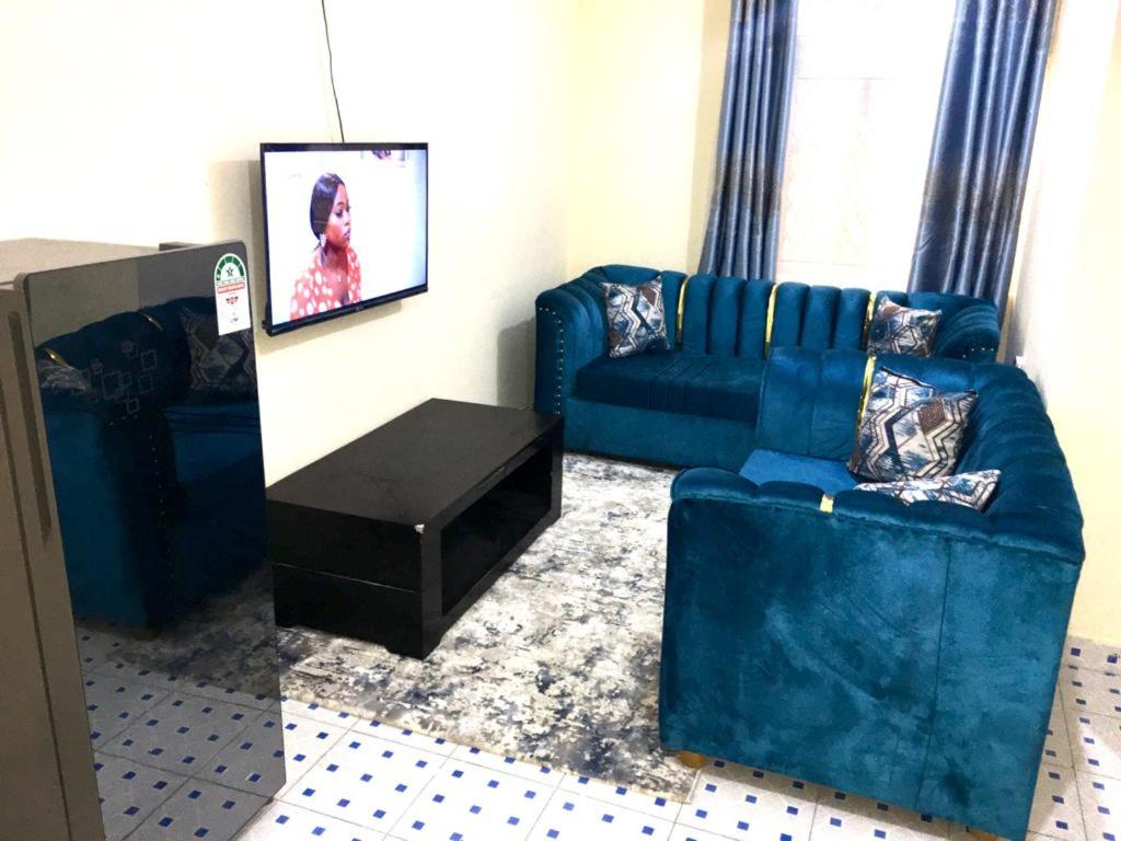 Vilma Apartment في مومباسا: غرفة معيشة مع أريكة زرقاء وطاولة