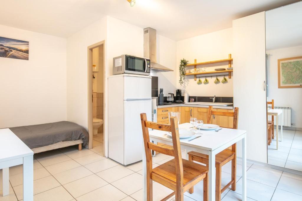 a kitchen and dining room with a table and a refrigerator at Studio 4 Vercors - Terrasse et parking Privé in Meylan