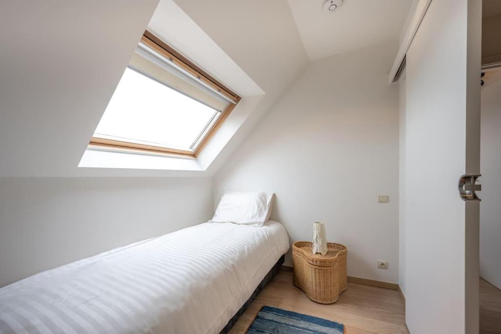 een witte kamer met een bed en een raam bij Locarno in Knokke-Heist