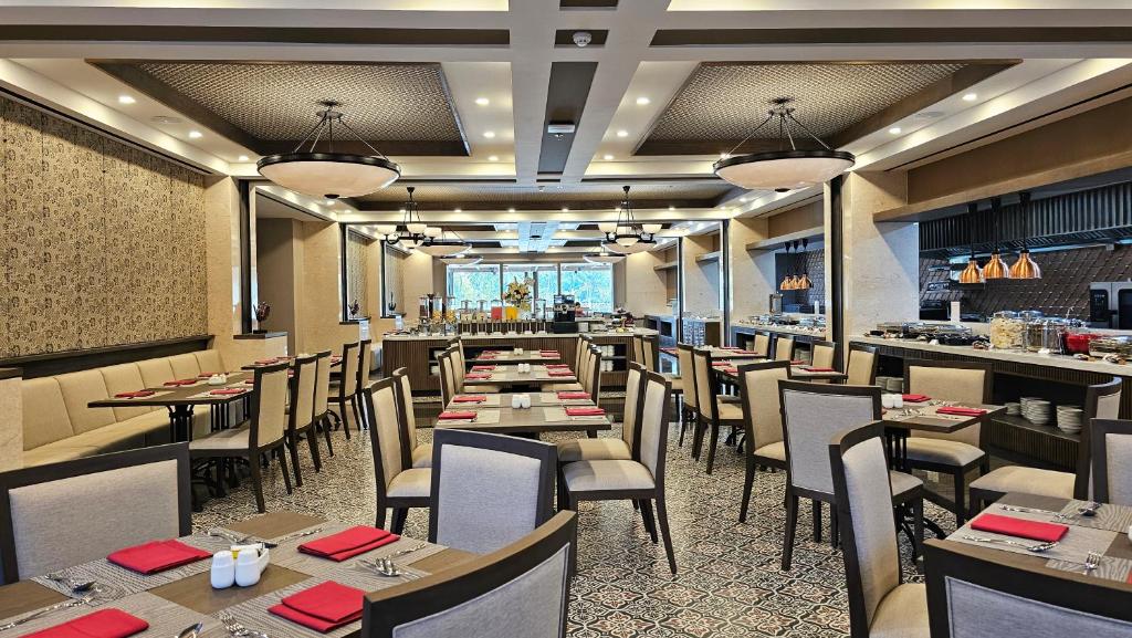 a dining room with tables and chairs in a restaurant at Swiss-Belhotel Airport Yogyakarta in Yogyakarta