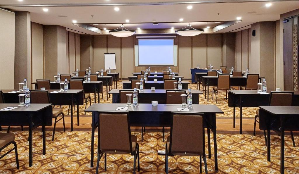 a conference room with tables and chairs and a screen at Swiss-Belhotel Airport Yogyakarta in Yogyakarta