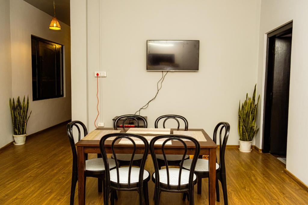 einen Esstisch mit Stühlen und einen TV an der Wand in der Unterkunft Solo's Inn in Kohīma