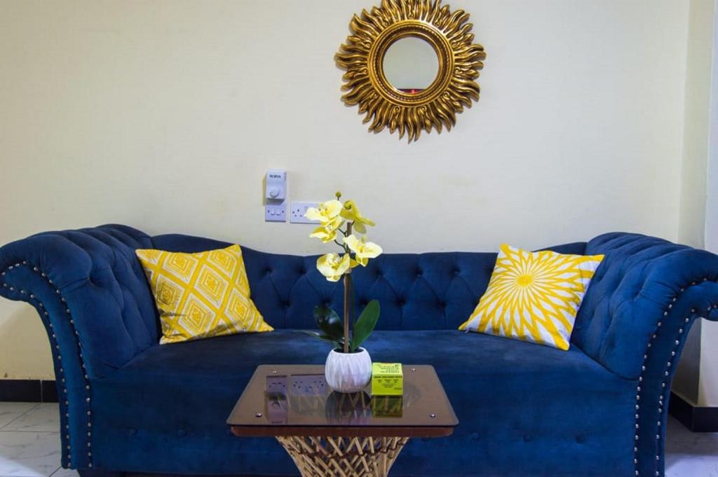 um sofá azul com almofadas amarelas e uma mesa em Roma Stays - Spacious Studio in Nyali opp Retna Square Close to Nyali Cinemax em Kisauni