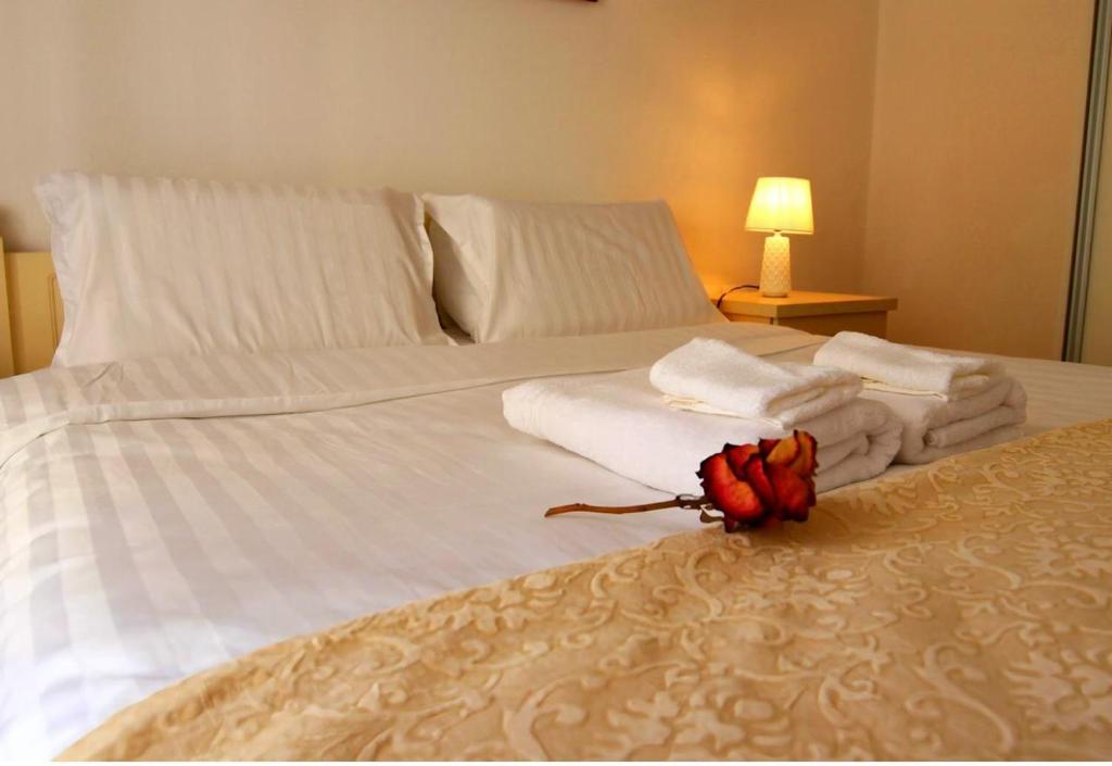 białe łóżko z ręcznikami i kwiatem w obiekcie The beautiful view w Tiranie