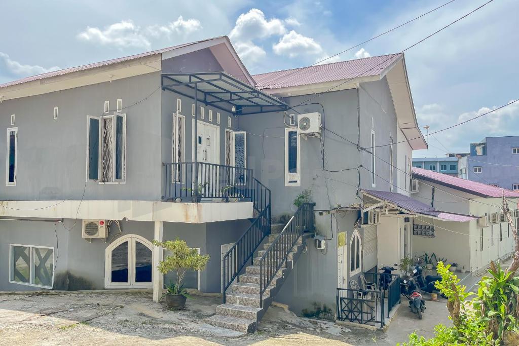 une maison blanche avec des escaliers en face de celle-ci dans l'établissement Namirah Guesthouse Redpartner, à Balikpapan