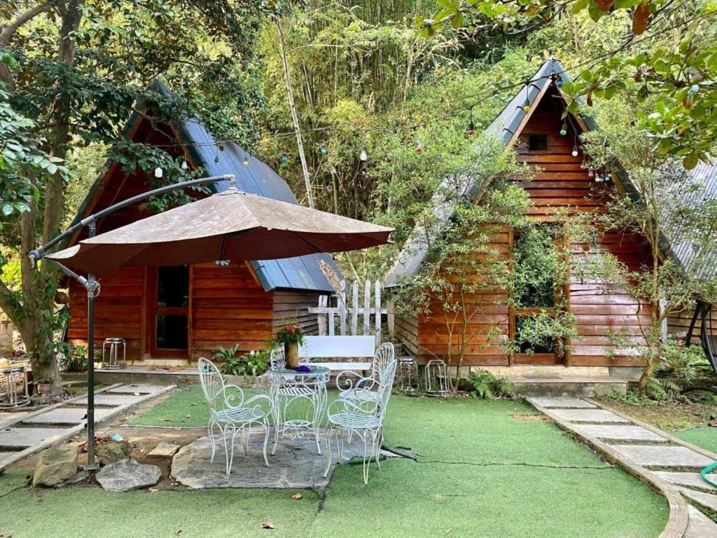 una mesa, sillas y una sombrilla frente a una cabaña en Eco Rose Homestay en Diện Biên Phủ