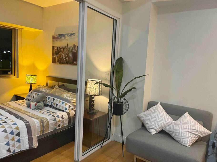 1 dormitorio con cama, sofá y espejo en Cool 1BR Acqua Livingstone w/ Netflix, Pool & Gym, en Manila