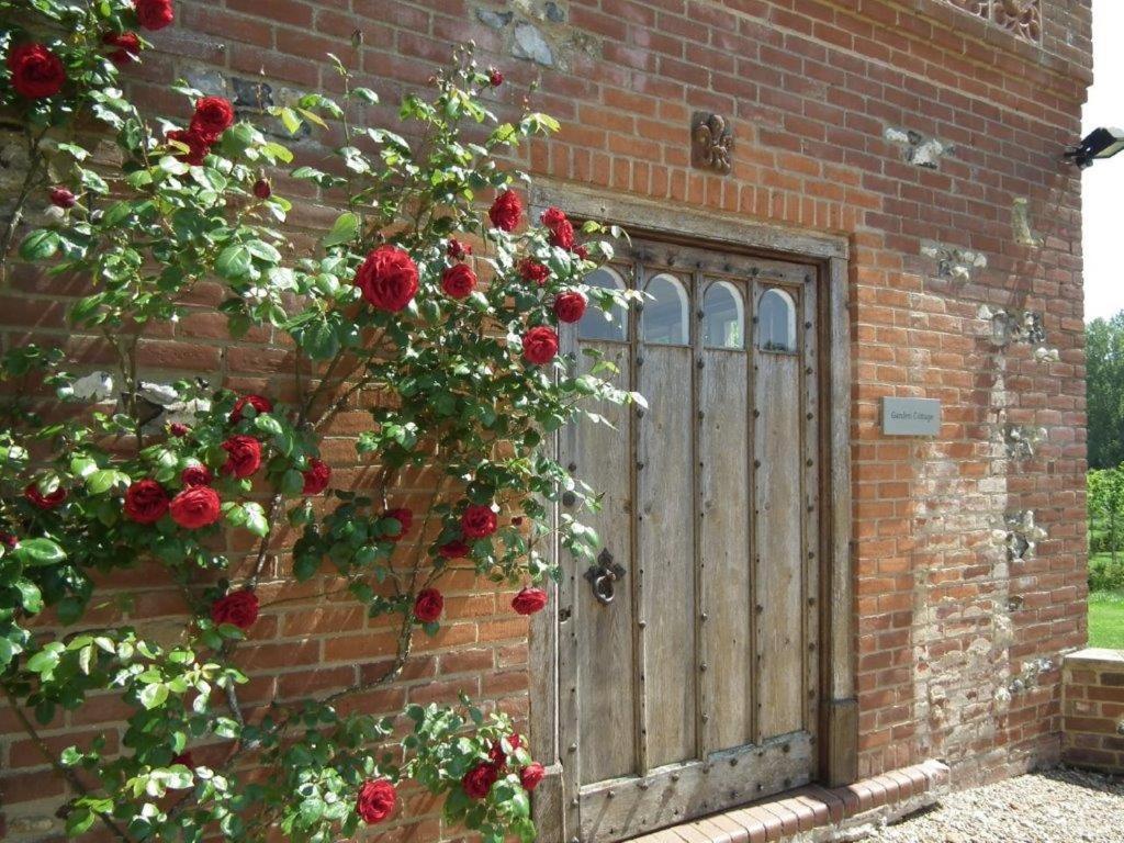 a brick building with a wooden door with red roses at Stunning Cottage in 15 acres in Brampton