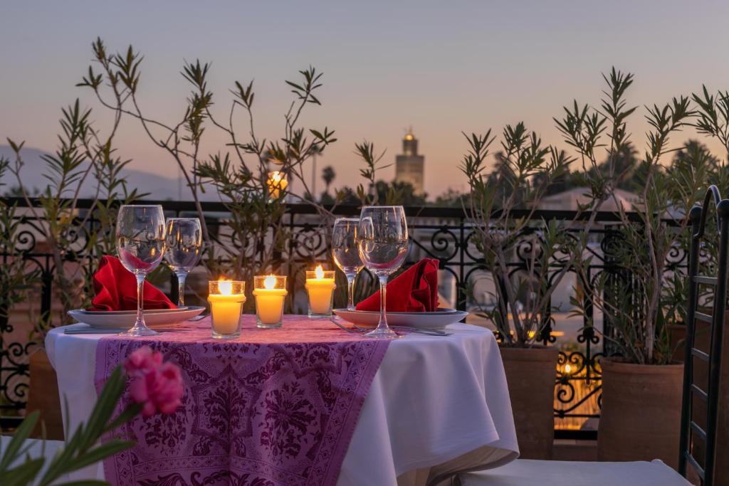 a table with wine glasses and candles on it at Riad Les Trois Palmiers El Bacha in Marrakesh