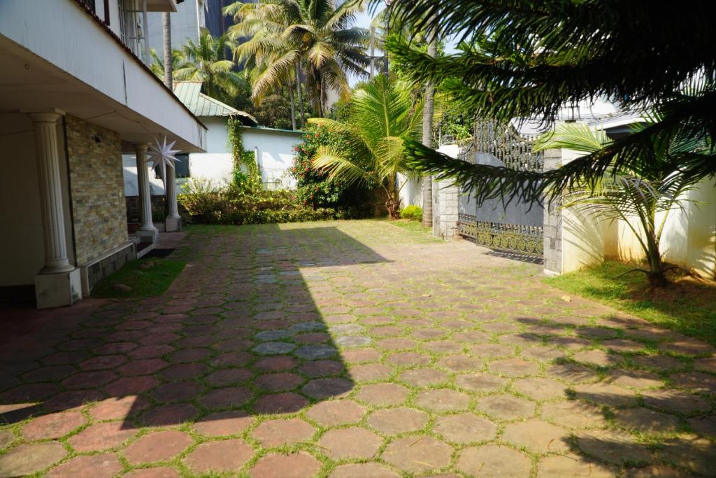 a brick walkway next to a building with palm trees at Ashleys Homestay in Cochin