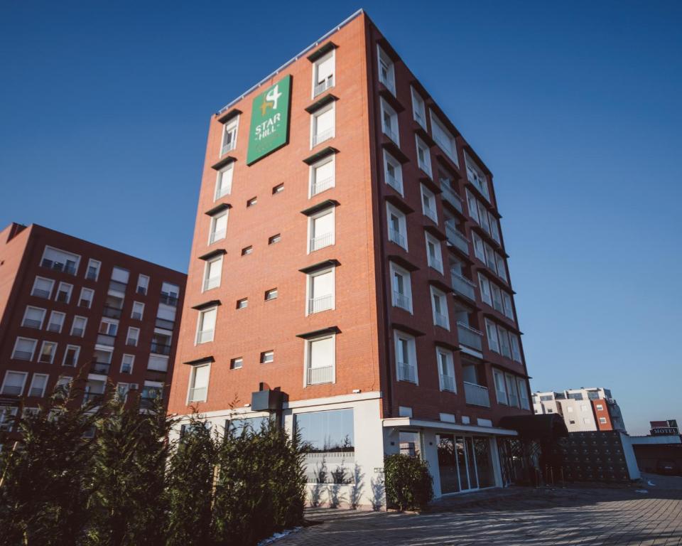 a tall red brick building with a green sign on it at Star Hill Hotel in Prishtinë