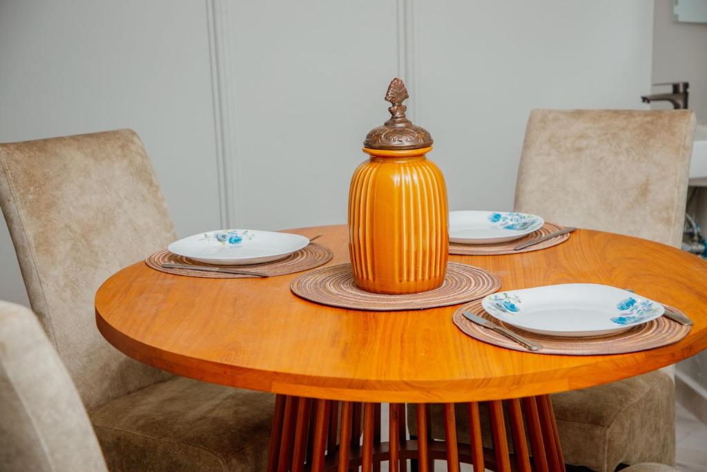 einem Holztisch mit Platten und einer Vase darauf in der Unterkunft Mahogany Mine Apartments-3 in Daressalam