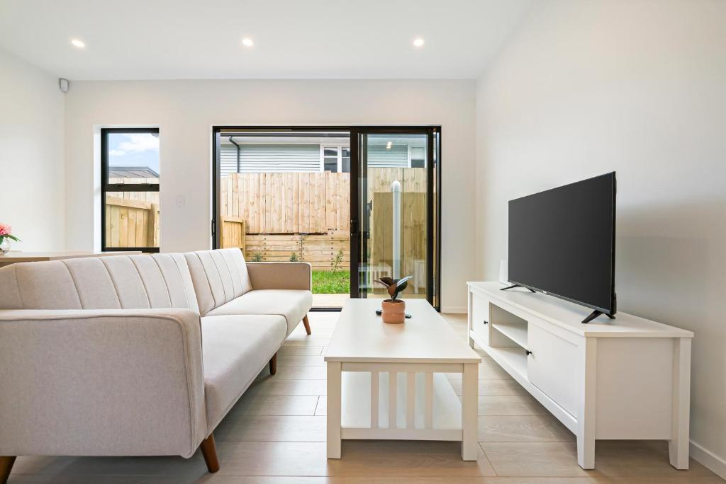 a living room with a white couch and a flat screen tv at Te Atatu Cozy Brand New House 4 in Auckland