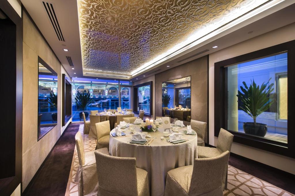 a dining room with tables and chairs and windows at The Fullerton Bay Hotel Singapore in Singapore