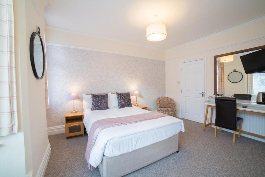 a bedroom with a bed and a desk and a sink at OYO Lonsdale Guest House in Oxford